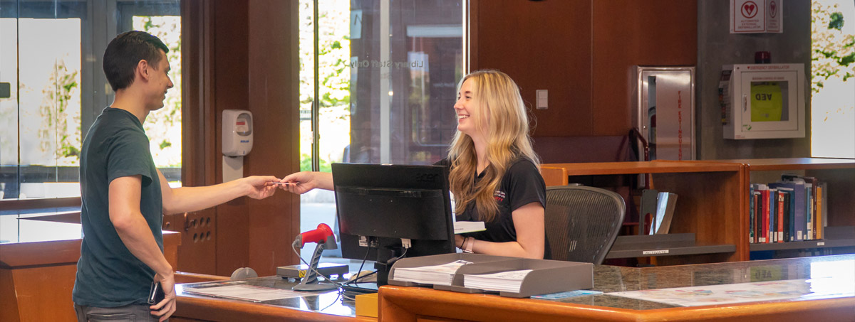 Student checking out a book at the 1st floor service desk