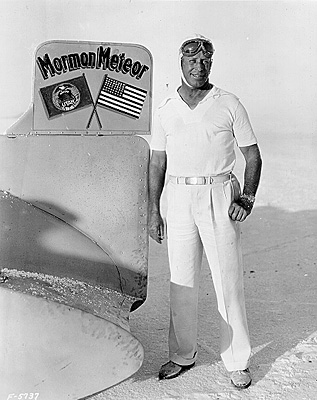 A man stands beside a plane marked with the words "Mormon Meteor," showcasing a unique aviation design