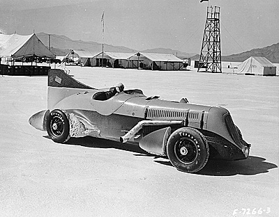 Race car on the white salt flats with buidling strucktures and mountainous background