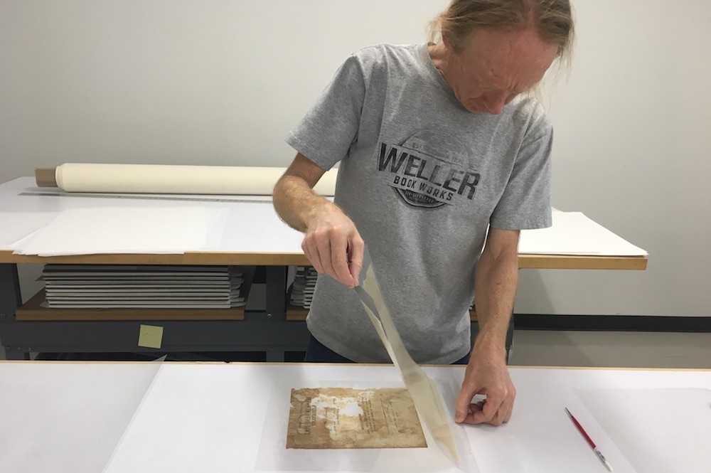 Book Conservator Jeff Hunt applying a lining to one of the pages