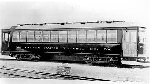 A vintage black and white image of an Ogden Rapid Transit Company streetcar, number 206, parked on railroad tracks.