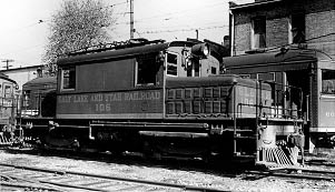 A vintage black and white photo of a small locomotive labeled "East Line and State Railroad 106" parked near railway cars.