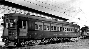 A vintage train car labeled "The Utah Idaho Central Railroad" parked beside a building, showcasing its historic design and structure.