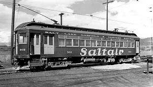 A vintage electric tram labeled "Saltair," with windows and wooden details, parked on tracks under a cloudy sky.